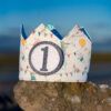 Corona de cumpleaños infantil hecha a mano en tela de algodón con animalitos y número 1, ideal para celebrar el primer cumpleaños de un bebé.