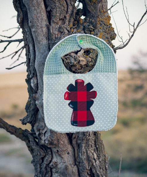 Babero infantil artesanal con aplicación de la Virgen del Pilar en tela de cachirulo y gofre verde.