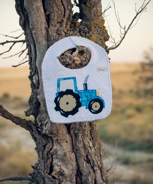 Babero infantil artesanal con aplicación de un tractor.