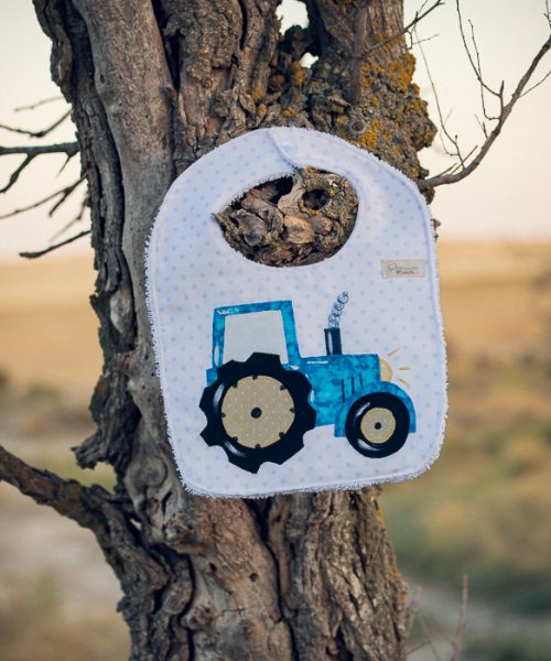 Babero infantil artesanal con aplicación de un tractor.