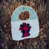Babero infantil artesanal con aplicación de la Virgen del Pilar en tela de cachirulo y gofre verde.