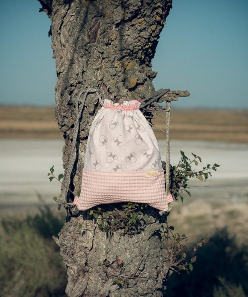 Mochila infantil pequeña de tela con estampado de lazos sobre fondo rosa hecha a mano.