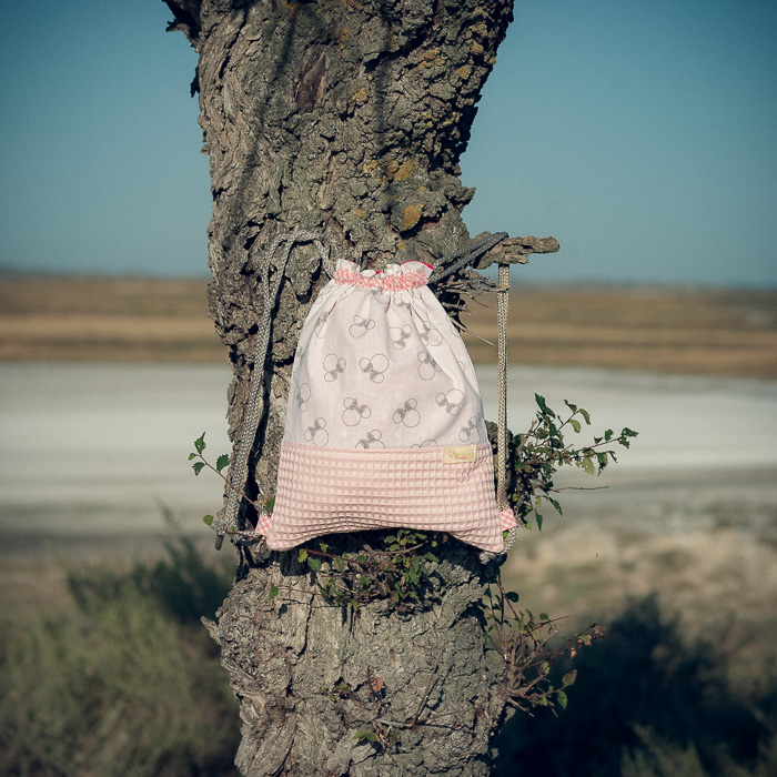Mochila infantil pequeña de tela con estampado de lazos sobre fondo rosa hecha a mano.