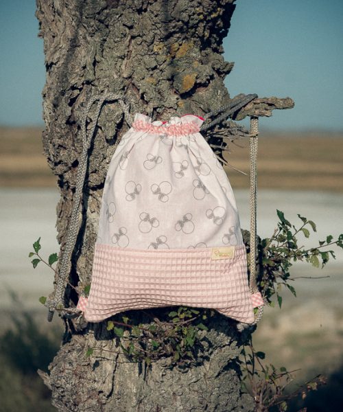 Mochila infantil pequeña de tela con estampado de lazos sobre fondo rosa hecha a mano.