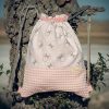 Mochila infantil pequeña de tela con estampado de lazos sobre fondo rosa hecha a mano.