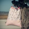 Mochila infantil pequeña de tela con estampado de lazos sobre fondo rosa hecha a mano.