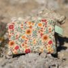 Monedero hecho a mano con estampado floral en tonos cálidos sobre fondo claro